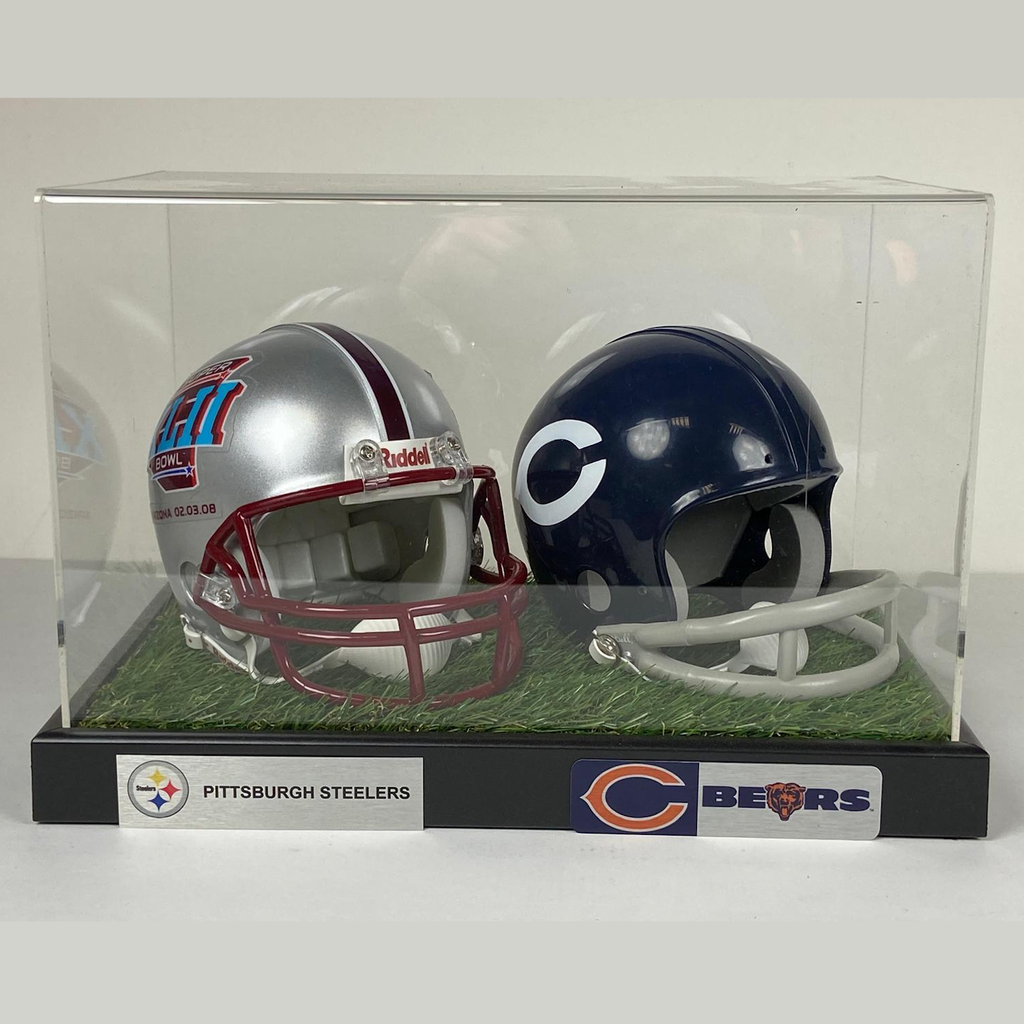Two miniature football helmets in a clear display case with grass base, one for Pittsburgh Steelers and one for Chicago Bears.