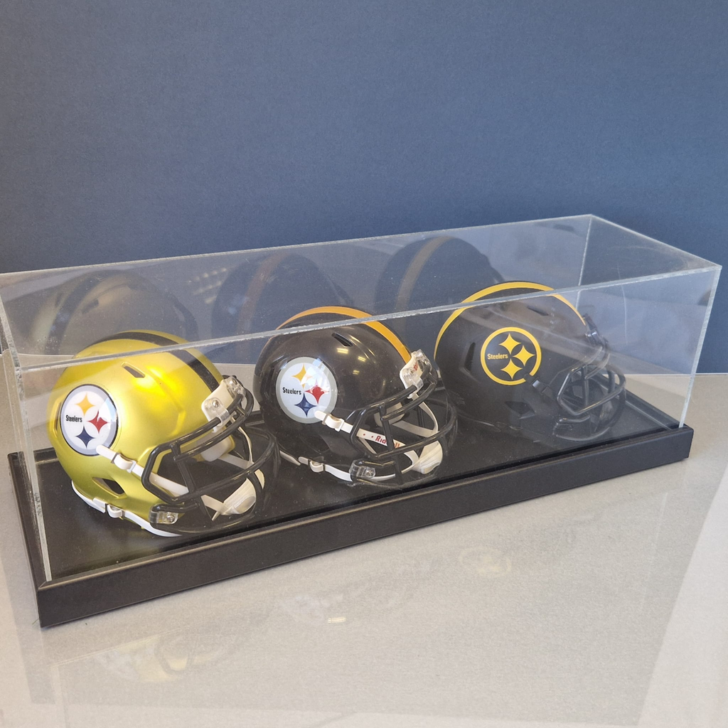 Three mini football helmets in a clear display case against a blue background
