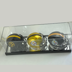 Three football helmets with logos in a clear display case on a white background