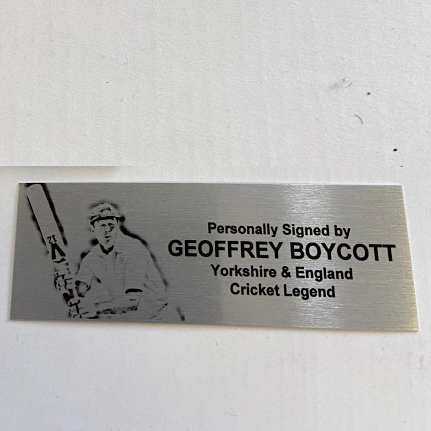 Metallic plaque with a silhouette of a cricket player and text about Geoffrey Boycott on a white background